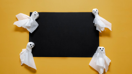 Homemade Halloween ghosts on a black and yellow background. Halloween concept. Place for inscription
