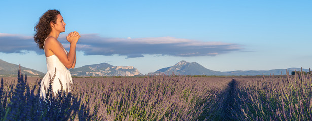 Christian worship and praise. A young woman is praying and worshiping in the evening. Worship and prayer banner. Lavender field.
