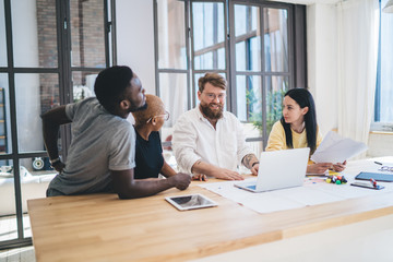Group of confident multiethnic coworkers using laptop in office
