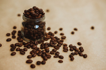 Coffee beans in a glass jar. Dark-colored roasted coffee beans on Kraft paper.