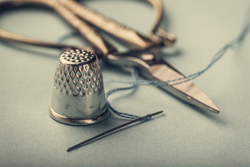 Vintage silver metal thimble and needle, scissors on blue background - obrazy, fototapety, plakaty