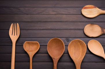 Wooden spoon and fork placed on an old black wooden table with space for designing text - top view.