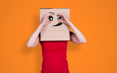 Person with cardboard box on its head looking into the distance by putting their hands around their...