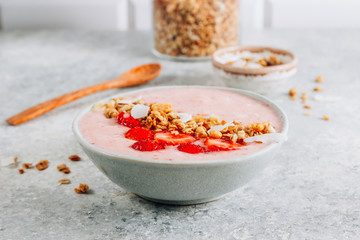 Fototapeta na wymiar Healthy banana and strawberrie smoothie in a bowl with pieces of strawberries, granola and coconut chips