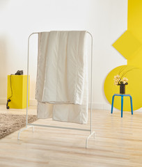 White quilt hang in the room, white and yellow background, round wooden style and coffee table.