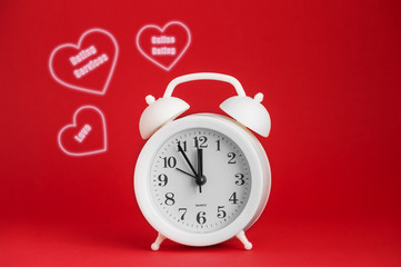 White round plastic alarm clock on a red background and the inscription in the hearts: online Dating, love. Red isolated background, close-up, copy space. The concept of online Dating