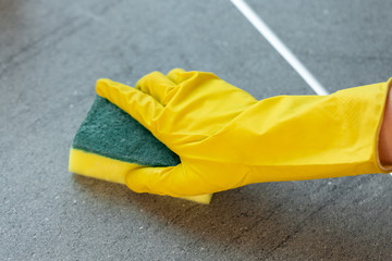 Woman's hands in yellow gloves cleaning counter top in kitchen