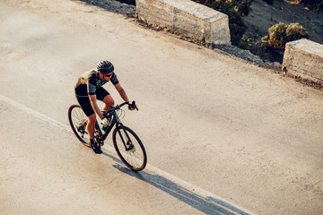 Naklejka premium Professional cyclist on a mountain road at sunrise