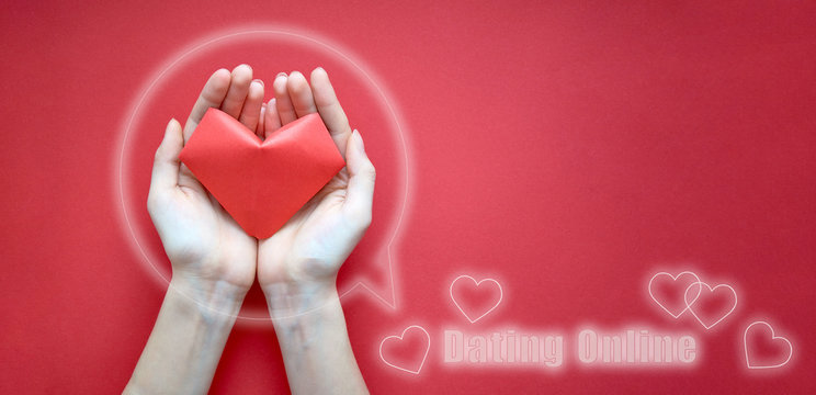 Women's hands are close-up holding a red paper heart inside the icon. Banner, copy space. The concept of online Dating. Ready-made template for the site
