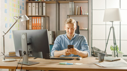 Creative Entrepreneur Sitting at His Desk Works on Desktop Computer in the Stylish Office, Picks up...