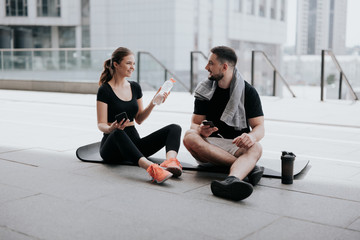 happy young couple handsome brunette man and beautiful woman in sportswear sitting on yoga mat,...
