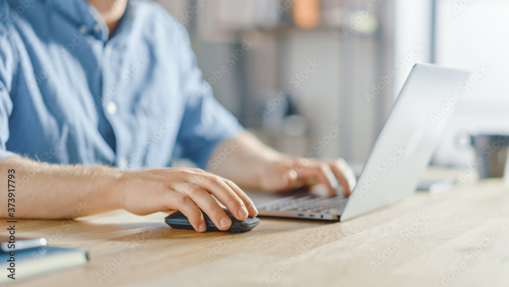 Poster anonymous businessman sitting at the wooden desk and working on a laptop, typing and writing busines
