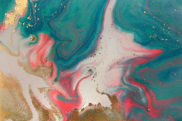 Piles of gold sequins on pink and blue smudges of paint. Abstract pattern.