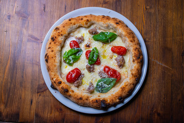 Pizza napoletana con pomodori, salsiccia, mozzarella e basilico 