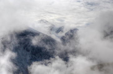 Natural background. Clouds float between high mountains. Soft focus. Selective focus on the mountain.