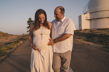 happy married couple - husband and his pregnant wife walk in autumn forest