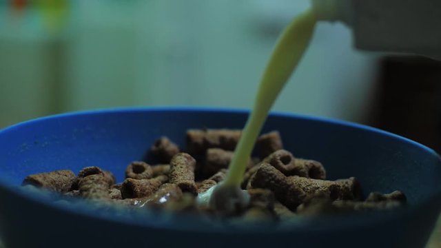 Pouring milk into a bowl of chocolate cereal.
Deitando leite numa ta&ccedil;a de cereais de chocolate.