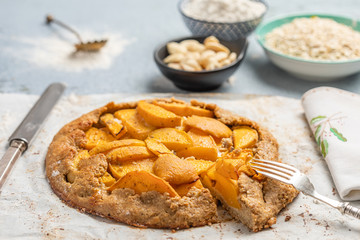 Peach cake, pie, blue background with a fork and a knife and bowls with the different ingredients. Front View