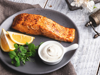 roasted baked salmon fillet with lemon, white sauce and pea sprouts, healthy food