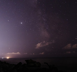 Many different constellations. Starry sky over the sea, the milky way and the lights of the night...