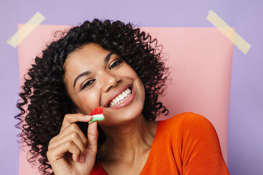 Image Of Joyful African American Woman Smiling While Eating Marmalade