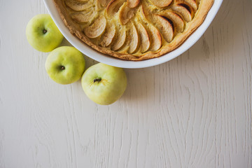 Apple pie with green apples. Part of the apple pie cooked at home in a white dish with three green...