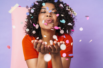Image of joyful african american woman making fun with confetti