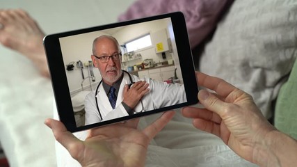 Woman engaged in a video conference with her doctor via telehealth or telemed on a wireless mobile device tablet pc. Male doctor giving health recommendations.