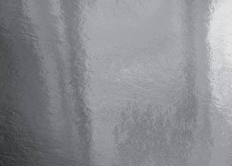 Silver foil texture background with highlights and uneven surface