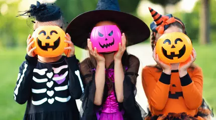 Tuinposter Happy Halloween! funny children in carnival costumes hide their heads behind buckets   pumpkins outdoors. © JenkoAtaman