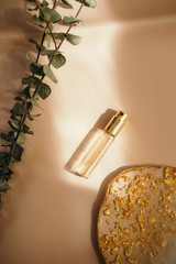 Fototapeta na wymiar Travel size perfume bottle on warm pastel and golden table