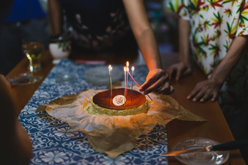 Fototapeta na wymiar Hands lighting the candles on a celebration birthday cake with family.