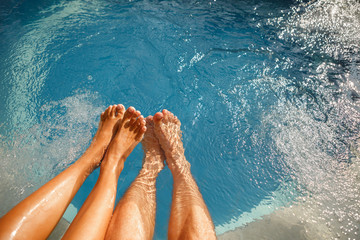 Happy romantic couple enjoying a bath in Jacuzzi. Male and female legs in the swimming pool. Young...