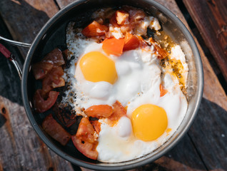 Delicious and healthy Breakfast. Fry eggs on a burner in nature and in the fresh air. Fried eggs with tomatoes close-up view from above.