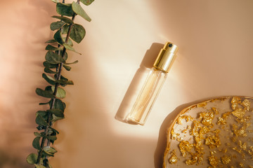 Travel size perfume bottle on warm pastel and golden table