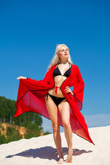 Sexy young beautiful blonde girl in black bikini and red tunic