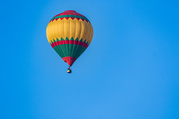 Hot air balloon in flight against a background of blue sky. Colorful balloon watercolor painting.