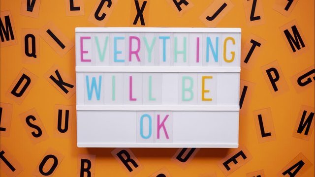 EVERYTHING WILL BE OK sign on a letter board with letters being animated around. Orange background.