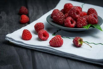 ripe raspberries on a plate on a light linen napkin. Selective focus.