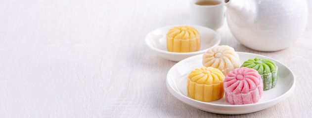 Colorful snow skin moon cake, sweet snowy mooncake, traditional savory dessert for Mid-Autumn Festival on bright wooden background, close up, lifestyle.