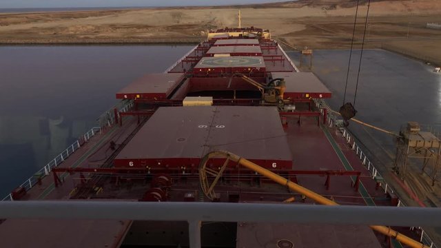 View at the bridge, discharging operation of a panamax size bulk carrier unloading grains cargo at the port of Duba, Saudi Arabia.