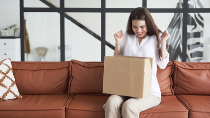 Young woman in casual clothes unpacking box