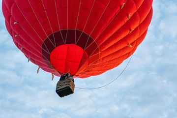 Red hot air balloon against blue cloudy sky