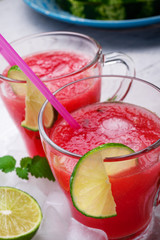 fresh vegetarian watermelon  cocktail in transporant cups on white table with fresh  watermelon,  lime, melissa. close up