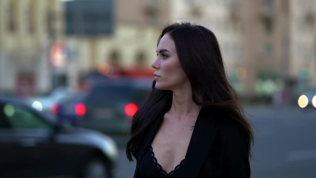 fashion model woman is walking in twilight on city street, medium portrait