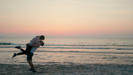 Young Happy Couple is Swirling from Happiness on Sea Beach at Sunset in Summer