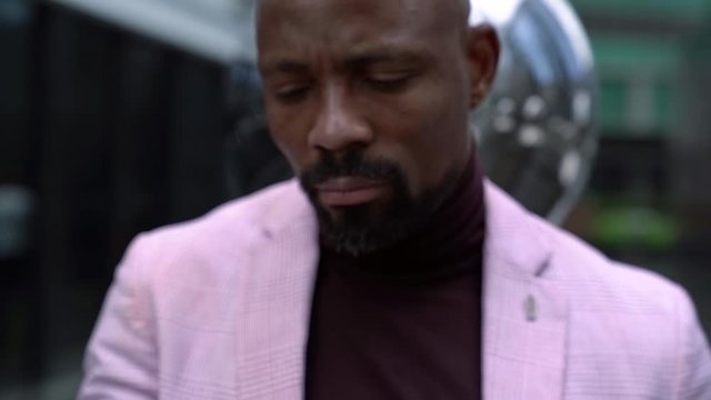 cool black man is holding and rotating metal balls in hand, looking at camera enigmatically