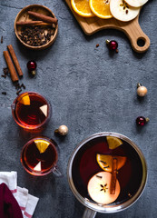 Pot and glasses of mulled wine. Mulled wine hot drink with citrus, apple and spices  on concrete background. Copy space. Flat lay.