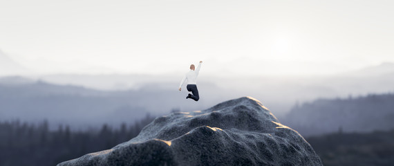 Businessman jumping for joy on the mountain. Success