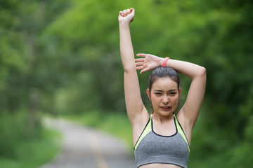 Portrait of a woman in sportswear stretching exercises after morning run in nature.